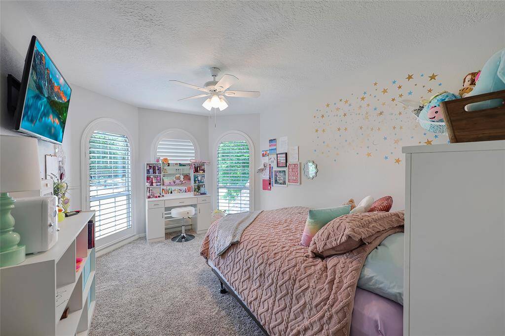 One of two upstairs bedrooms, the space is flooded with natural light from the arched windows with plantation shutters. The room also has a good sized walk-in closet.