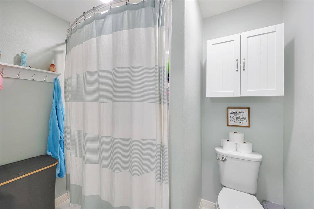 Separated from the sinks by a pocket door is the shower/tub combo and commode with storage above.
