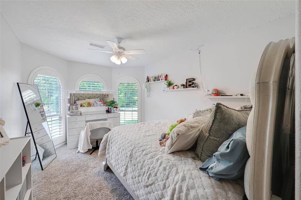 This second upstairs bedroom is light and airy, featuring arched windows that mirror those in the other bedroom, letting in loads of natural light.