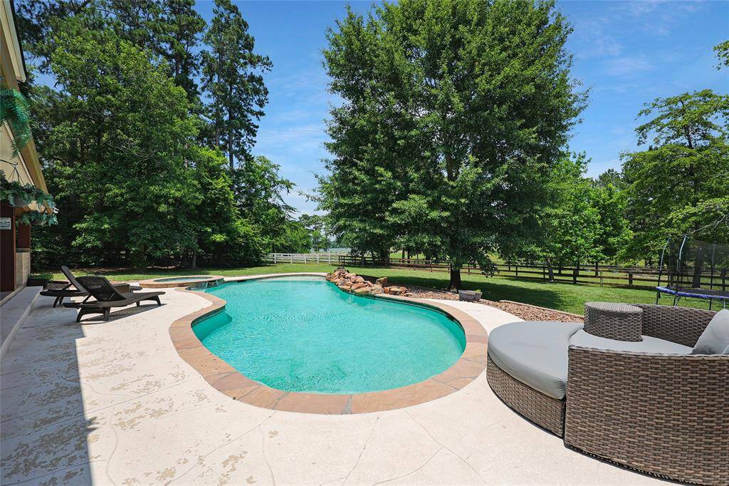 A sparkling in-ground pool with a soothing waterfall feature and connected spa offers a private backyard escape. Surrounded by lush greenery and mature trees, and a lake view the serene setting is ideal for both relaxation and fun.