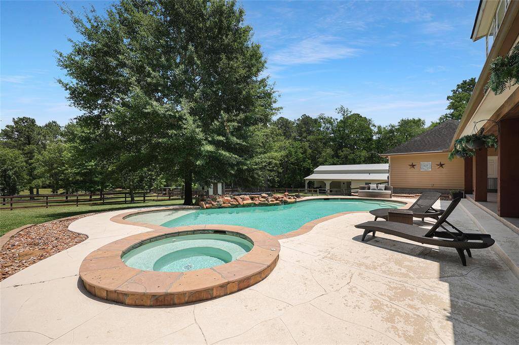 The poolside lounging area features ample space for sunbathing and seating with curved decking and natural stone accents. There's plenty of room to unwind or host summer pool parties.