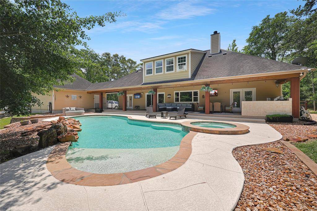The backyard showcases a seamless blend of natural landscaping and structured hardscaping, complete with an outdoor kitchen and ample seating and dining space—ideal for gatherings under the stars.