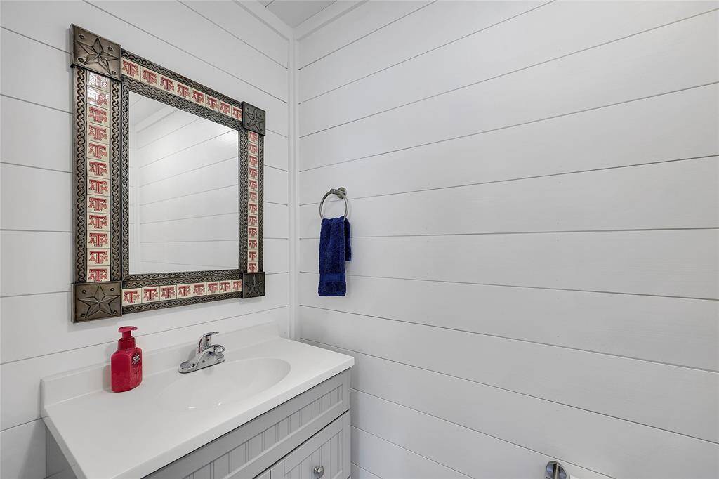 This 1/2 bath inside the metal building is great for guests getting in and out of the pool. It has wood plank walls and a very farmhouse bath type feel. Also, Gig 'Em!