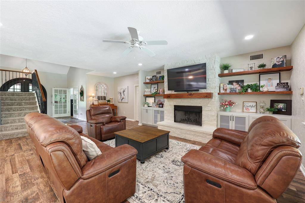 This custom white stone fireplace (wood burning/gas connection) with a rustic wood mantle, is perfect for cozy nights in. Flanking it are custom built-in shelves and cabinets providing a tasteful place to display decor, adding both style and storage.