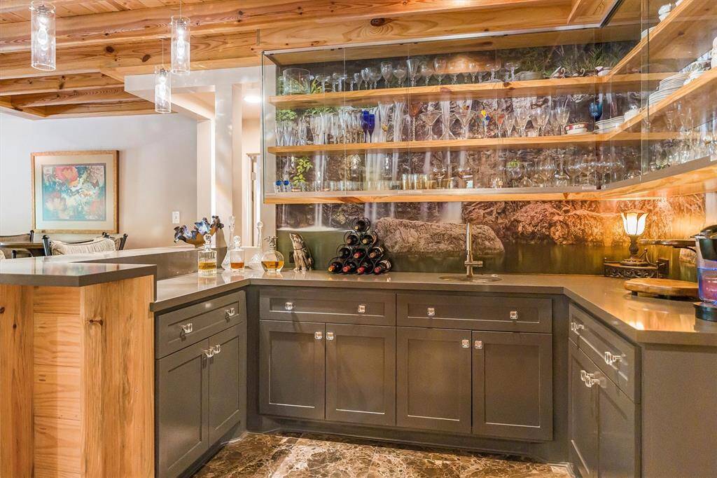 Beverage and coffee bar, wraparound spirit bar, custom cabinets with pull-out shelves, pounded nickel sink with push-button garbage disposal.