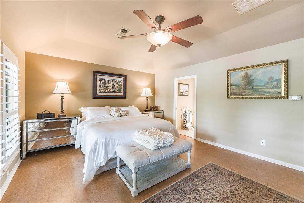 Primary suite with cork flooring, lake view, deck access, and plantation shutters.