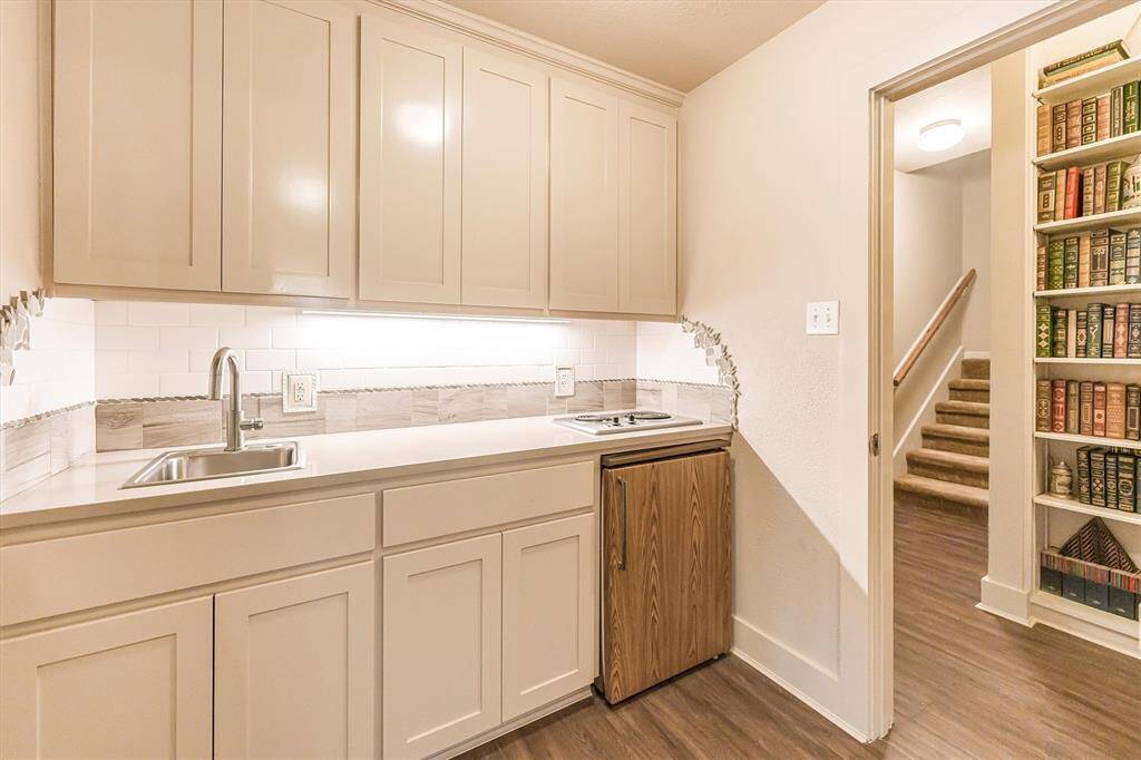Full private suite with kitchenette including stovetop, refrigerator, sink, and custom cabinets