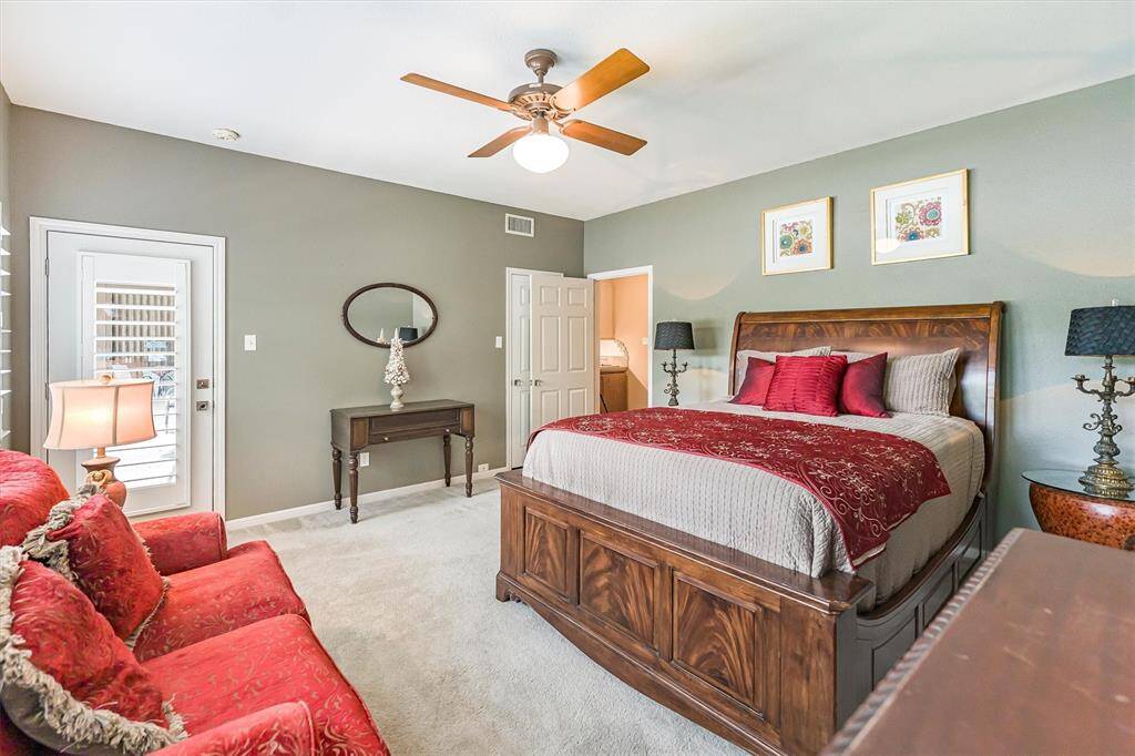 Carpeted bedroom with plantation shutters, serene lake views, and private access to patio and pool
