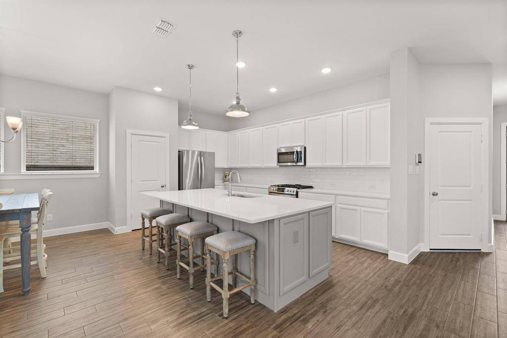 Light and bright kitchen complete with white cabinets and backsplash, breakfast bar and more!