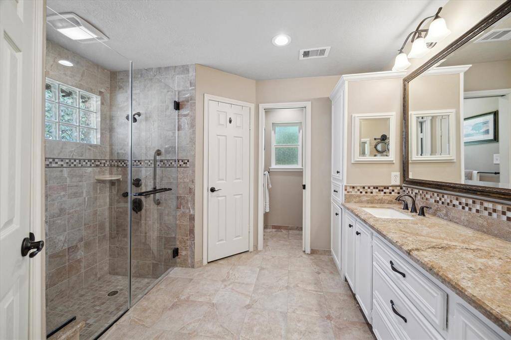 Elegant primary bathroom with glass shower, dual sinks, and generous mirror space.