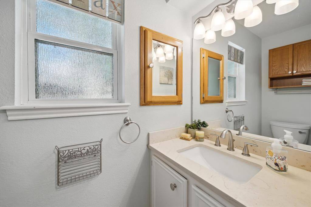 Stylish half bath with single sink, large mirror, and sconce lighting.