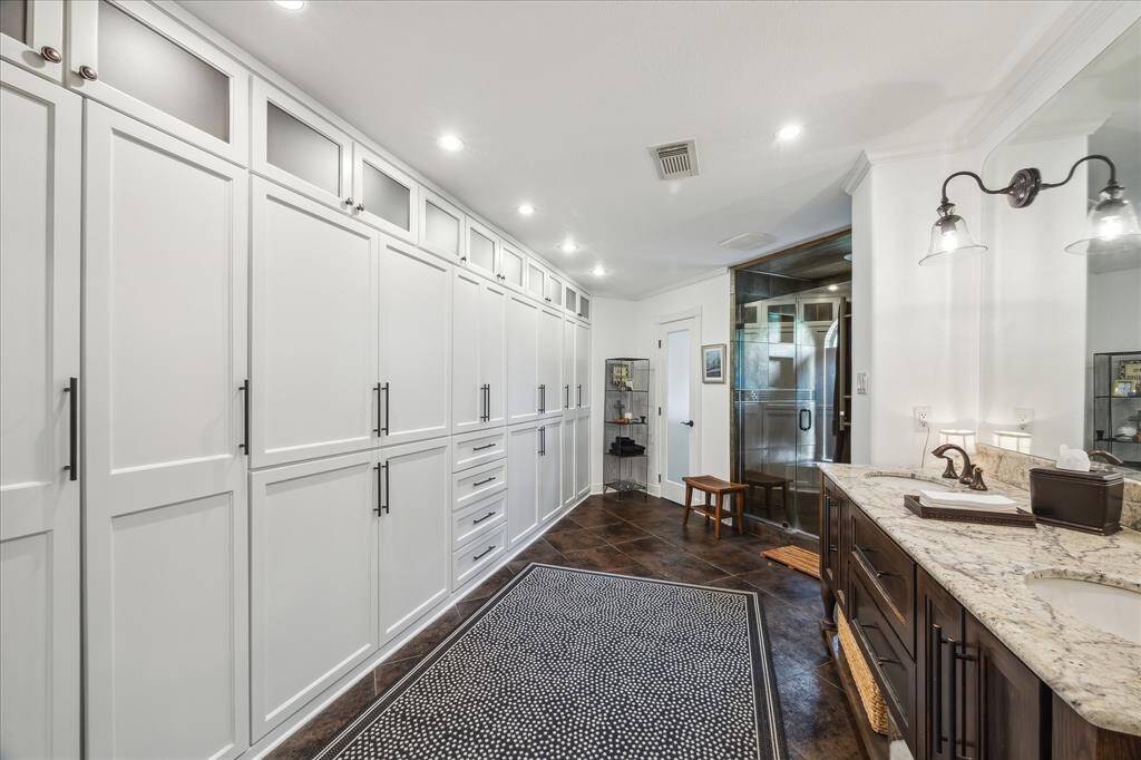 The primary bathroom has a custom-built vanity with double sinks, a walk-in shower with a towel warmer built in, and custom built in closets.