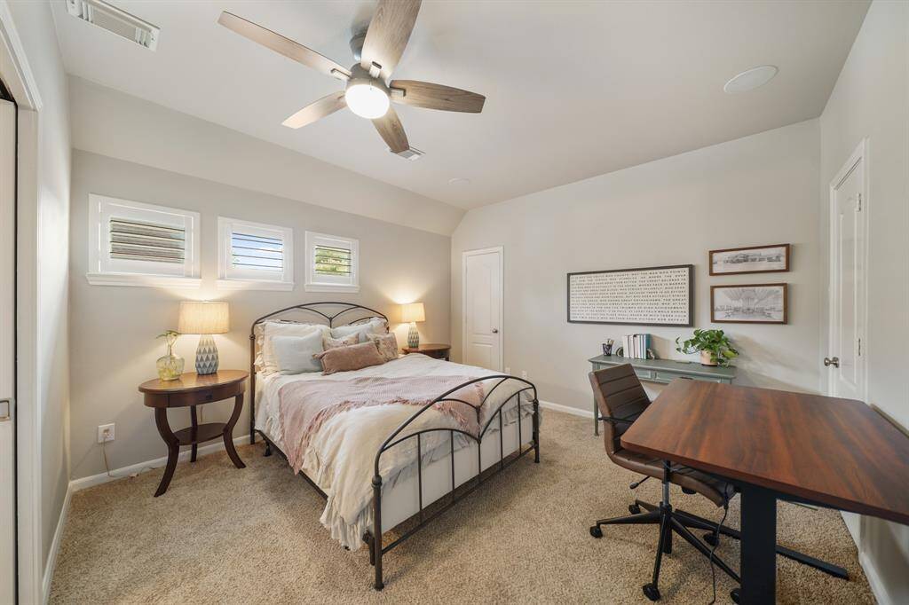Carpeted upstairs Secondary Bedroom with a ceiling fan and architectural details