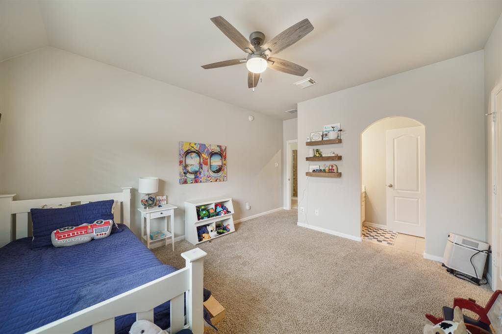 Carpeted upstairs Secondary Bedroom with a ceiling fan and architectural details