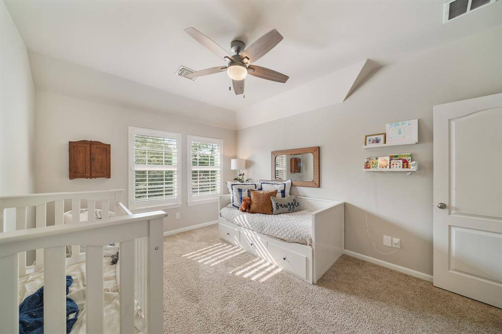 Carpeted upstairs Secondary Bedroom with a ceiling fan and architectural details
