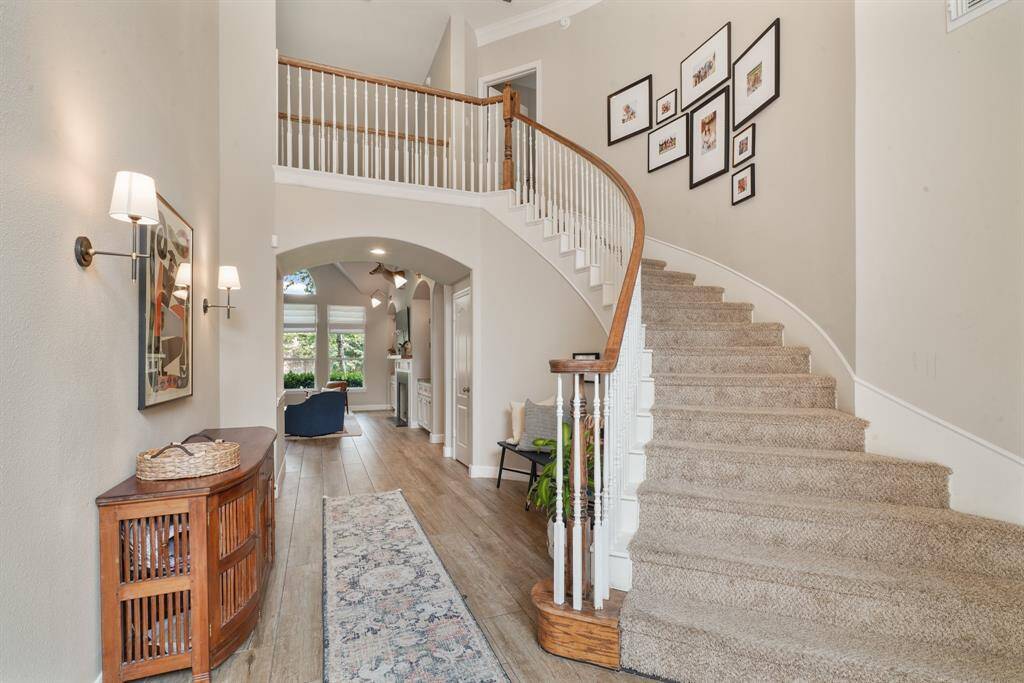 Grand, carpeted staircase leading to the second-floor landing that looks over the front and back of the house