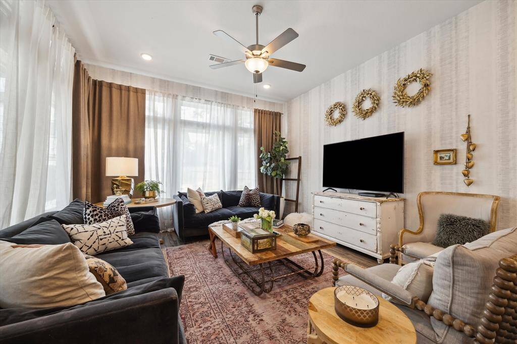 Generous space meets cozy charm in a living room framed by big windows and bathed in sunlight