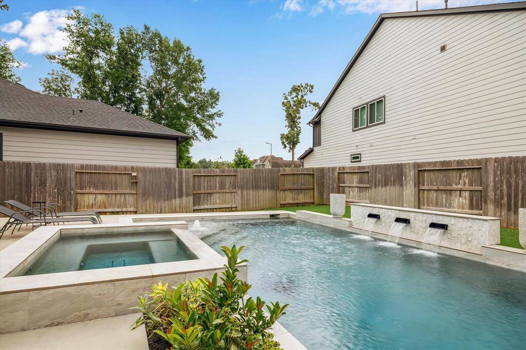Enjoy the calming sound of water features and the luxury of a jacuzzi in your fenced backyard pool.