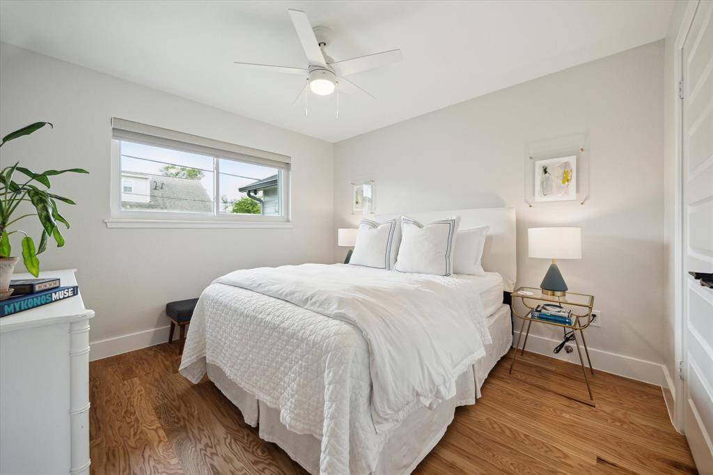 Located across from the primary bedroom, this inviting SECONDARY BEDROOM has brand-new engineered wood flooring, a ceiling fan for comfort, and a spacious double-door closet. A large window with a new shade allows for natural light.
