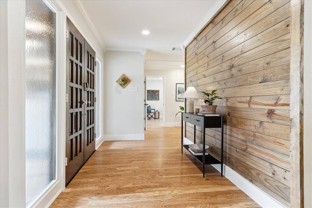 Clean lines and a natural wood accent wall create a seamless transition into the living/dining and kitchen area on the right and the bedroom area on the left.