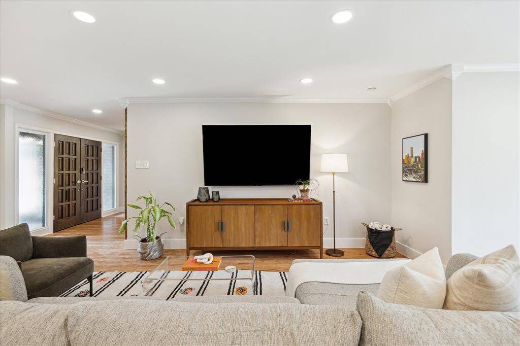 The living area opens to the kitchen and dining spaces. New engineered wood flooring extends throughout the living and bedroom areas.