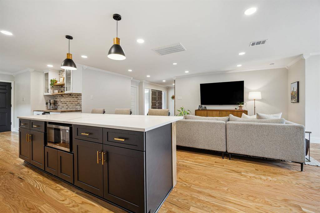 The expansive island seats 3-4 comfortably, stretching nearly nine feet wide and illuminated by elegant pendant lighting above