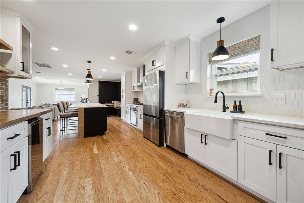 This kitchen is sure to impress! On the left, is the wine and breakfast bar, while the porcelain sink is ideally placed beneath a window, highlighted by a pendant light above. Just off the kitchen (not pictured) is a convenient laundry room, complete with LG washer and dryer