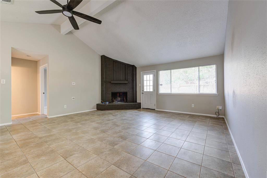 The painted brick fireplace creates a cozy centerpiece, while tile flooring offers a fresh, modern look—perfect for relaxing or entertaining family and friends.