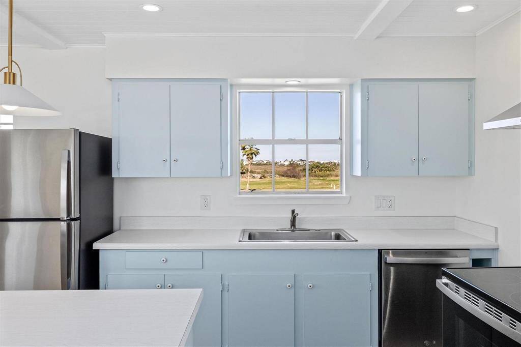 Kitchen with recessed lighting, ornamental molding, a sink, light countertops, and appliances with stainless steel finishes