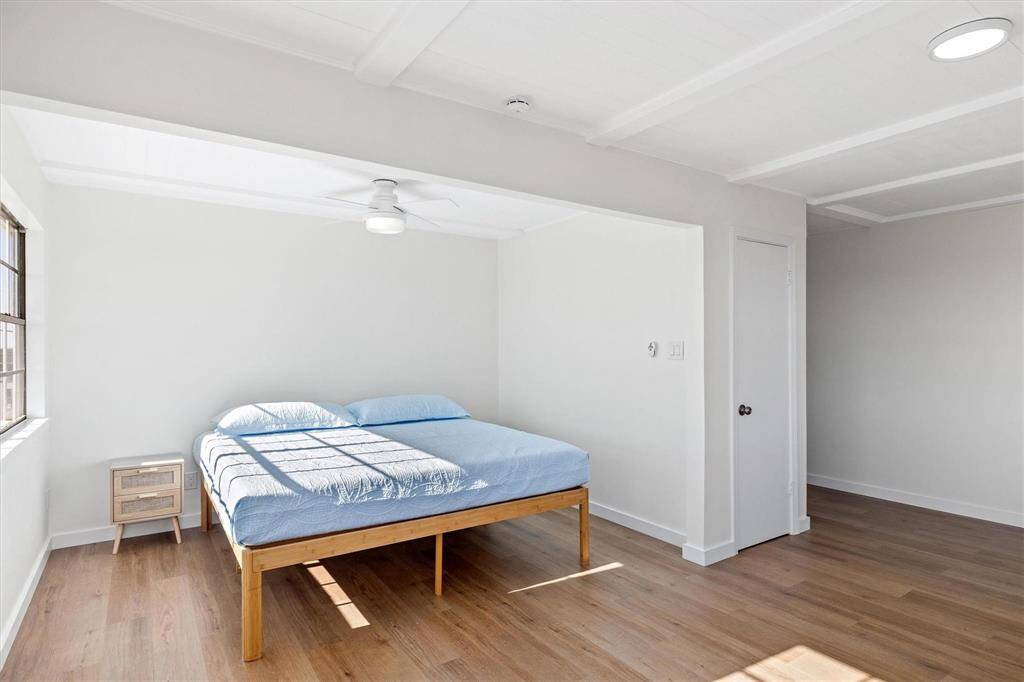 Bedroom with baseboards, beam ceiling, ceiling fan, and light wood finished floors