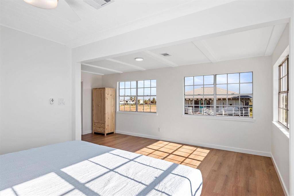 Unfurnished bedroom featuring visible vents, baseboards, beamed ceiling, and wood finished floors