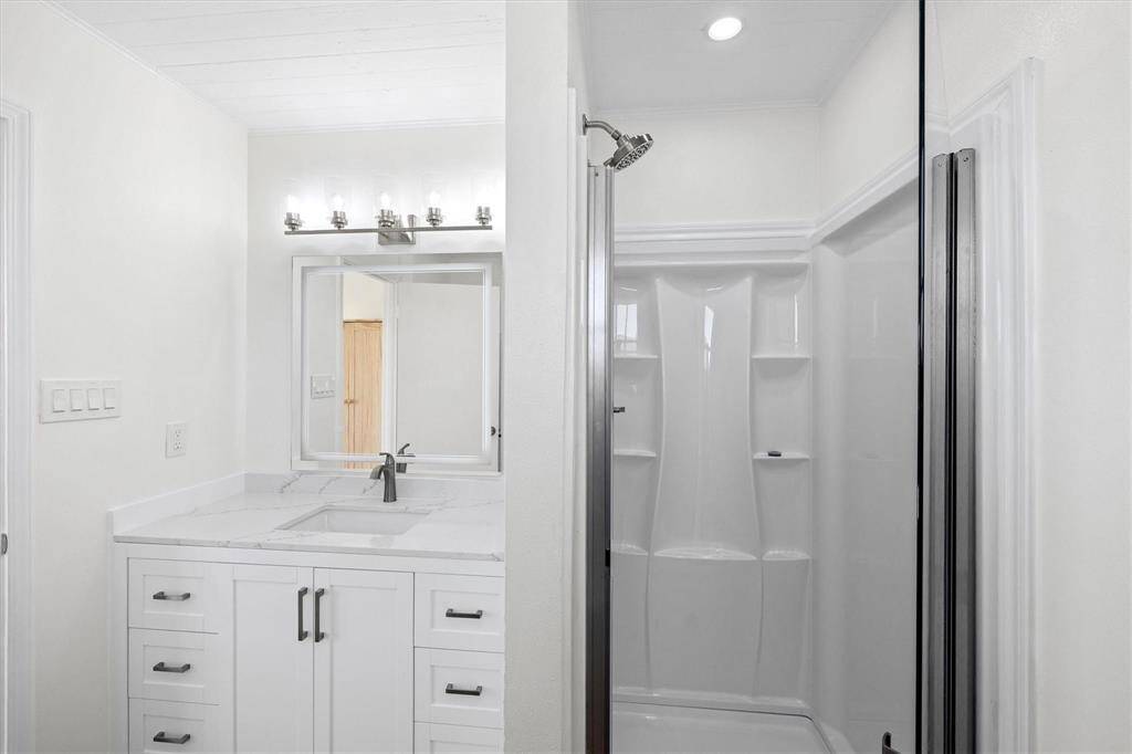 Bathroom featuring walk in shower, ornamental molding, and vanity