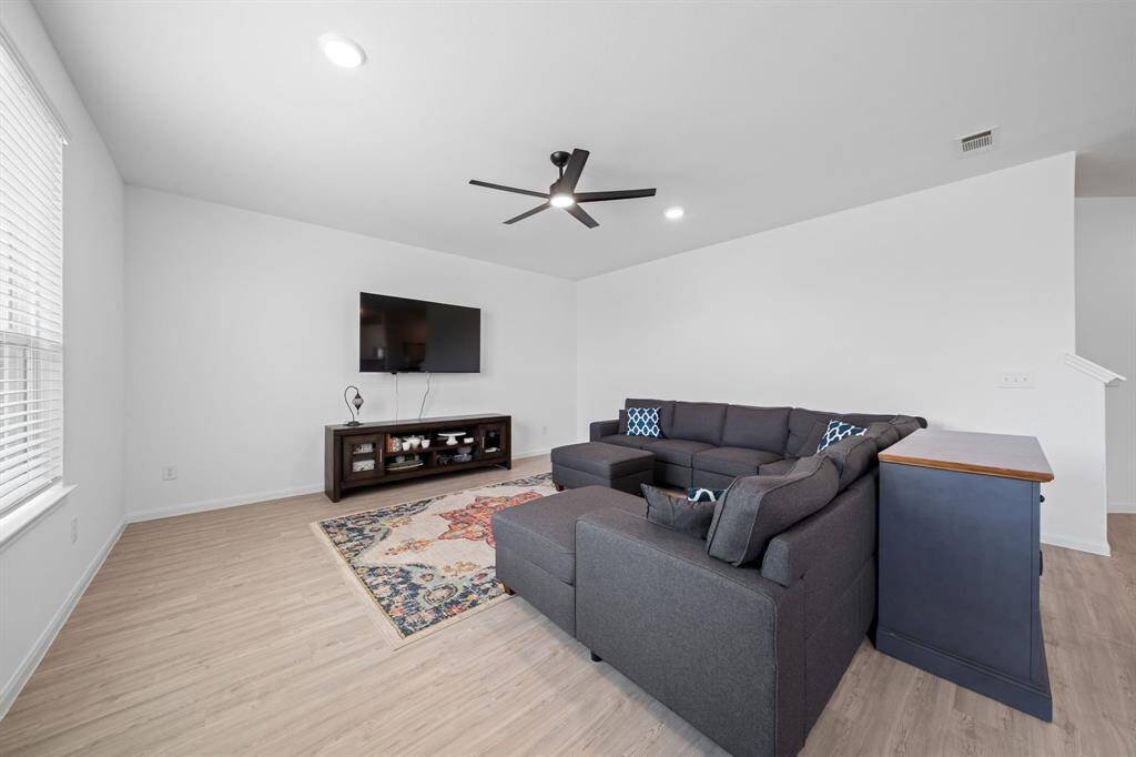 The living area features a ceiling fan and sits adjacent to the kitchen and dining spaces, enhancing the open-concept design.