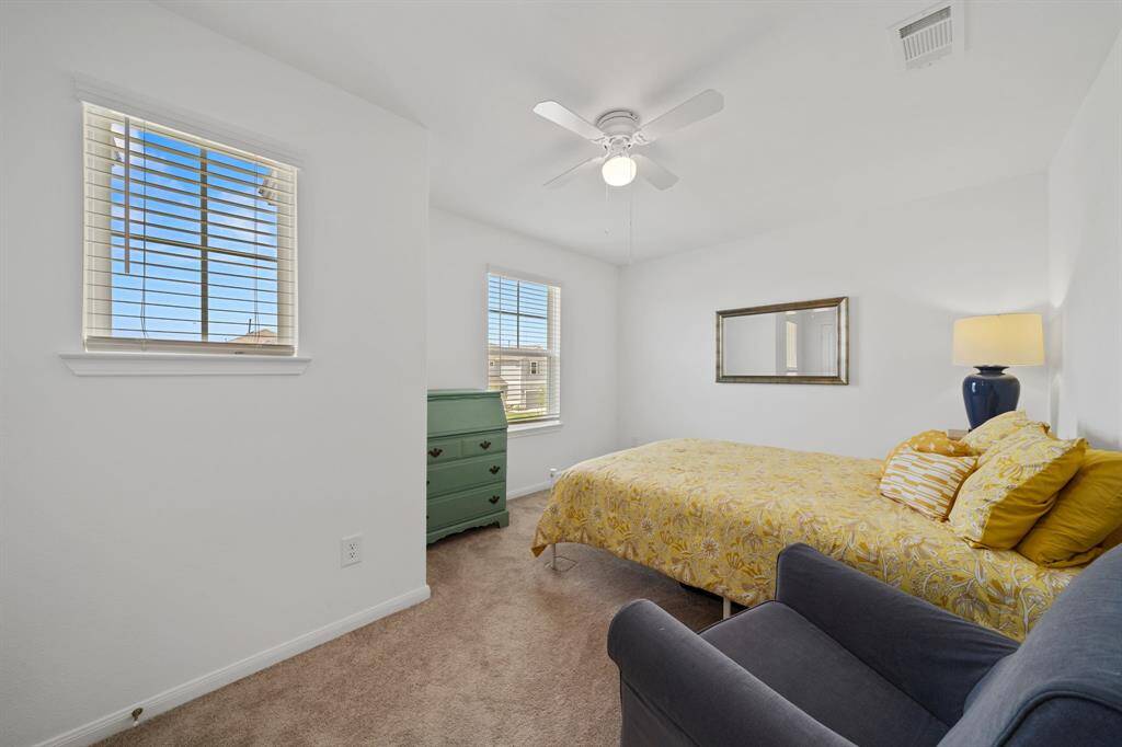 Spacious upstairs front room features plush carpeting and a ceiling fan, offering versatility as a bedroom or second living area.
