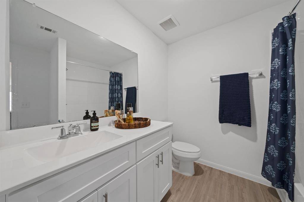 Stylish full bath showcases durable LVP flooring and cabinetry with modern hardware for a clean, updated look.