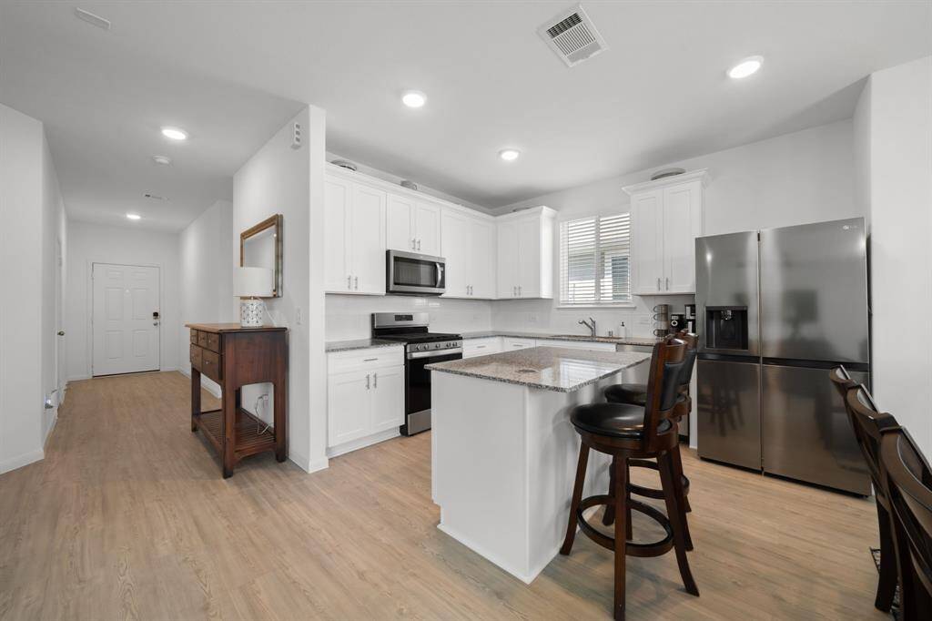 The kitchen features crisp white cabinets with silver hardware, offering a fresh and modern look.An island with a breakfast bar adds extra prep space and casual seating for everyday meals.