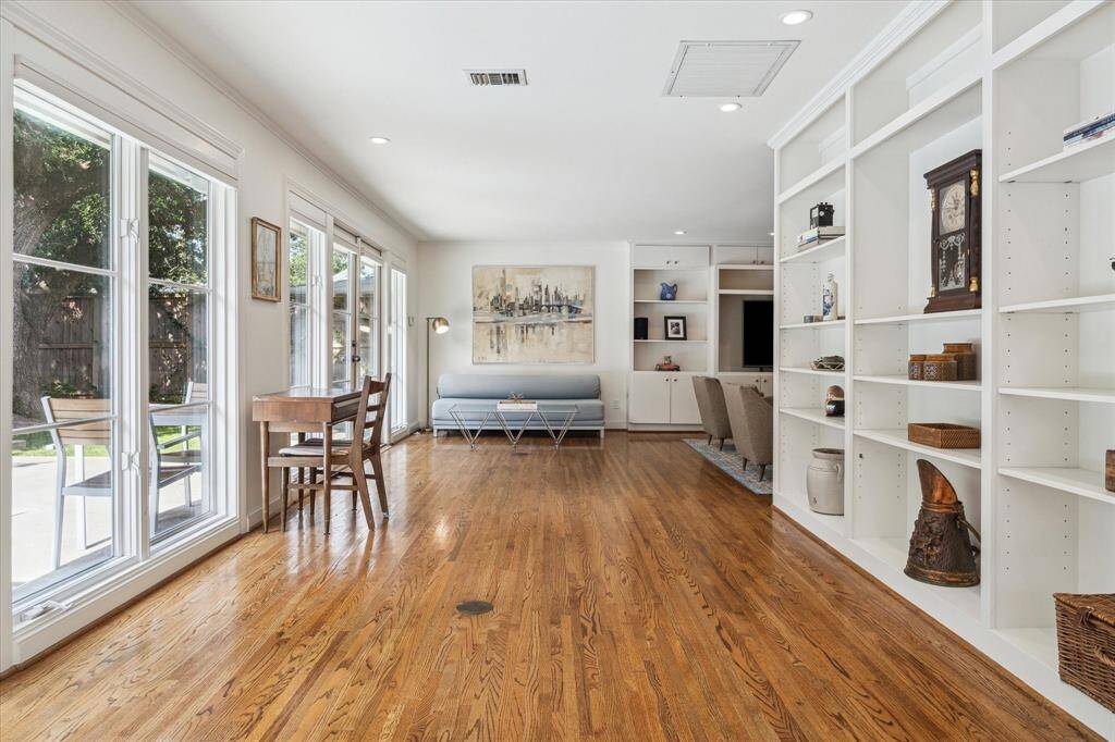 The den stretches the width of the house and features a wall of built-in shelves and another wall of windows overlooking the backyard and pool. How would you use this room? Study, library, sunroom, art studio, playroom?