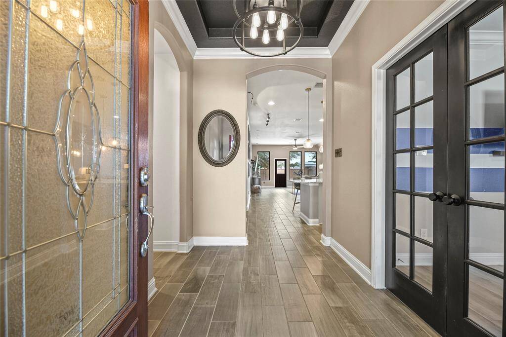 Step through the leaded glass door into a bright foyer with eye-catching tile floors, a cool trayed ceiling, and a chandelier that adds just the right touch of charm.