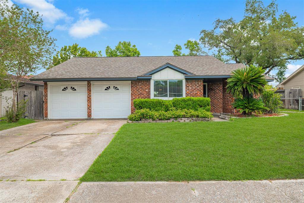 Charming single-story brick home with dual garage doors. This home offers a suburban feel but centrally located in the city. The property features a welcoming entrance with lush greenery and mature trees, providing excellent curb appeal.