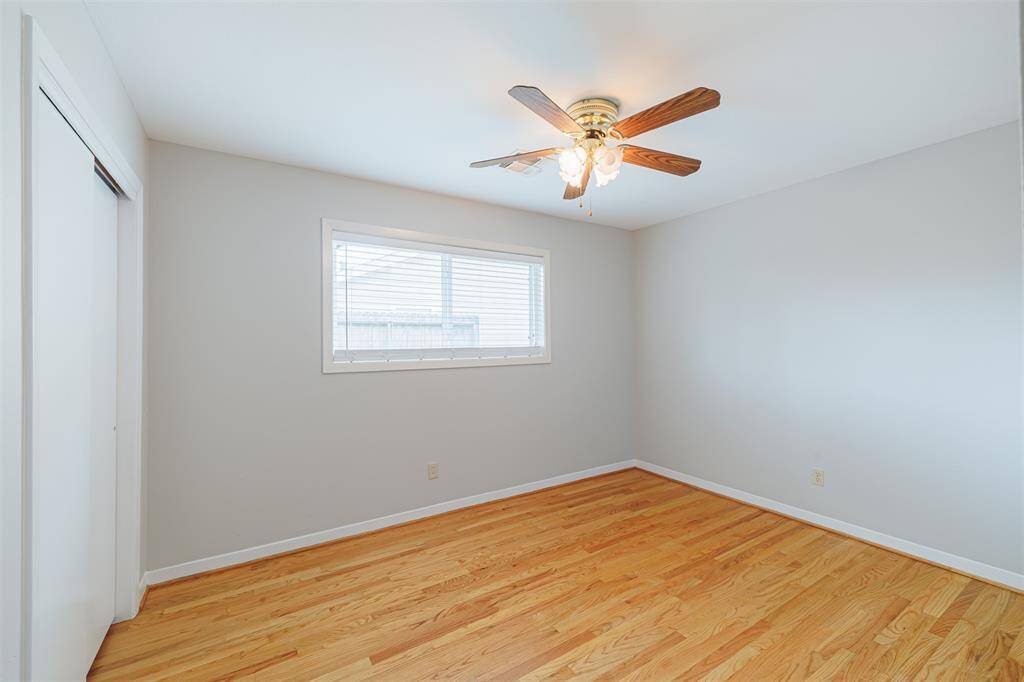 Second bedroom with ceiling fan and hardwood floors.