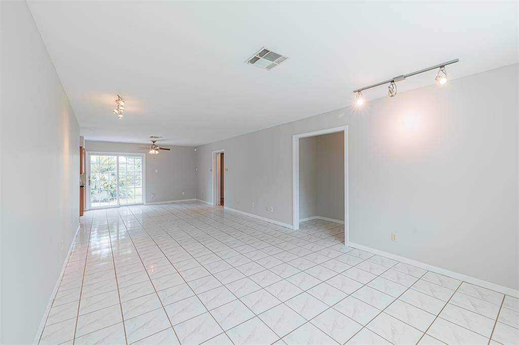 Dining, living, and seating area with tile floors. View looking toward dining room and sliding back door that leads to the large shaded backyard.