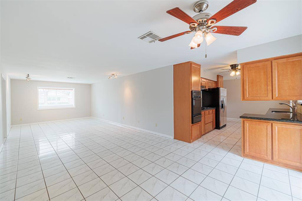 Dining, living, and seating area with tile floors.  View from dining to front of house with bay window.  View from dining room with kitchen on the right and bedrooms on the left.
