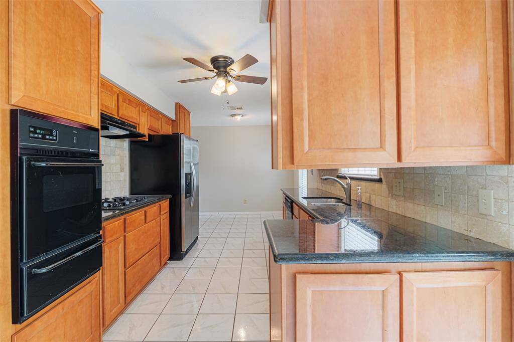 Updated kitchen with granite countertops, gas cooktop, stainless refrigerator, and microwave.  View towards garage.