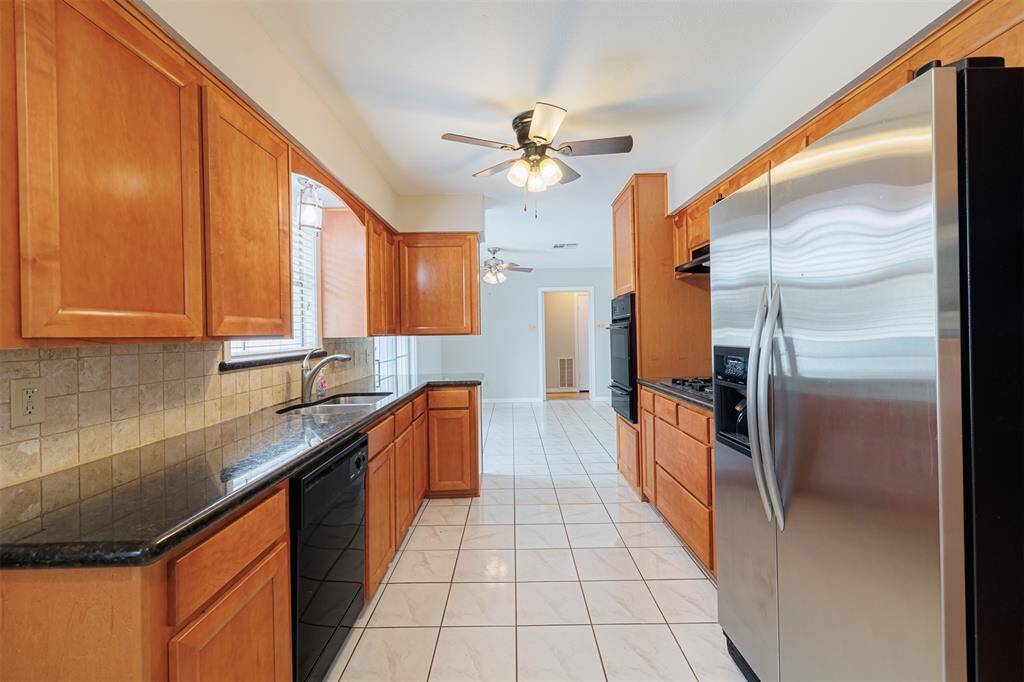 Updated kitchen with granite countertops, gas cooktop, stainless refrigerator, and microwave.  View towards dining room.
