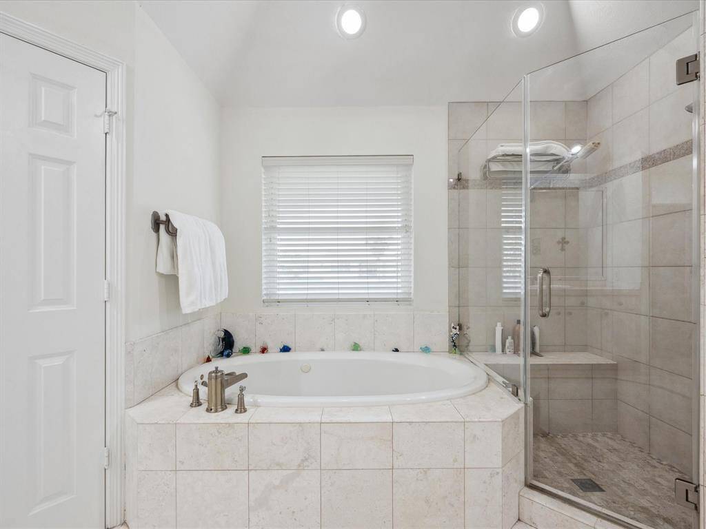 THE BATH IS FINISHED WITH A WHIRLPOOL TUB AND A WALK-IN SHOWER WITH FRAMELESS GLASS ENCLOSURE.
