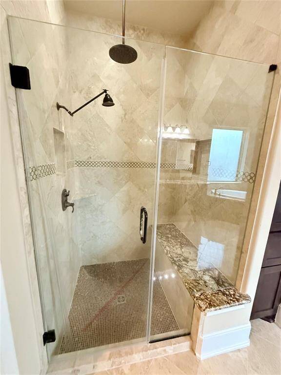 Primary bathroom offers frameless shower, built-in granite bench and a rainfall shower head.