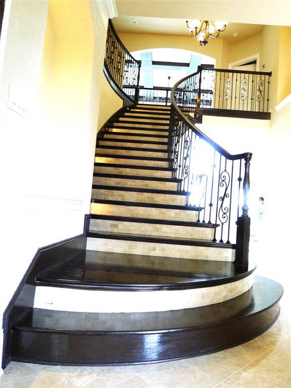 Awesome spiral rich hardwood stairs case with fancy wrought iron railing.