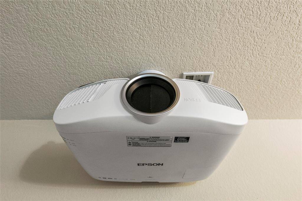 The media room features a sleek Epson ceiling-mounted projector, seamlessly integrated to deliver crisp, vibrant visuals.