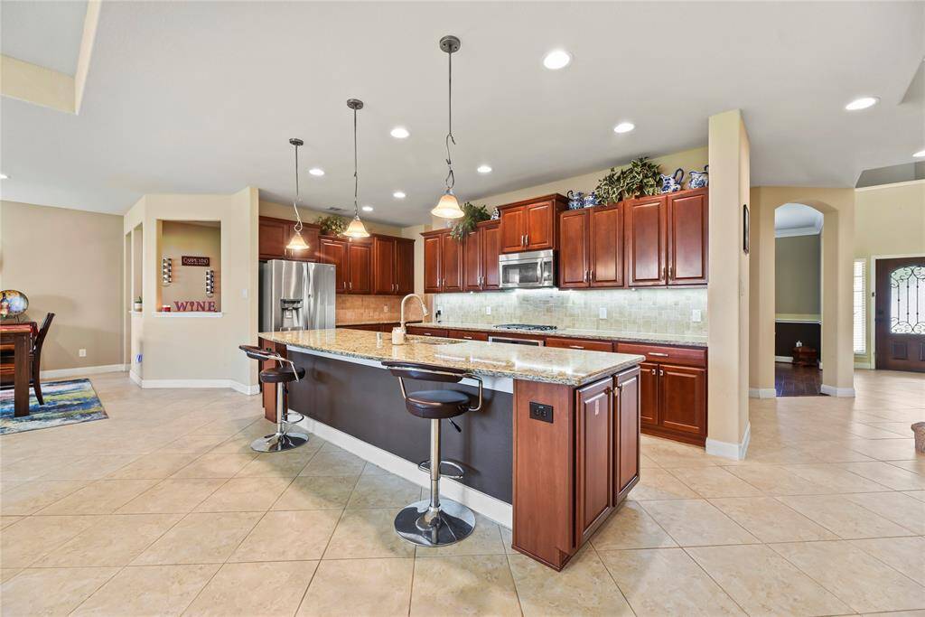 Your chef inspired kitchen awaits! Features include granite countertops paired with a coordinating stone backsplash, stainless steel appliances, rich cabinets with updated hardware, under cabinet lighting, recessed lighting, pendant lighting and a sprawling island with breakfast bar seating.