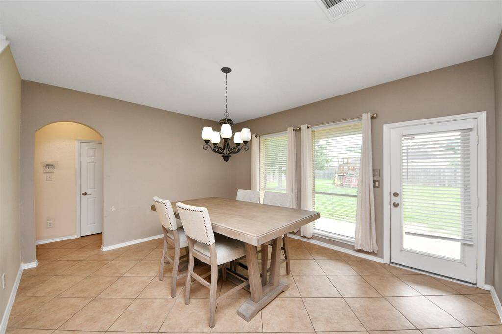 Beside the kitchen, this dining space is bathed in daylight thanks to nearly floor-to-ceiling windows. A glass-paneled door leads to the backyard, making indoor-outdoor dining a breeze.